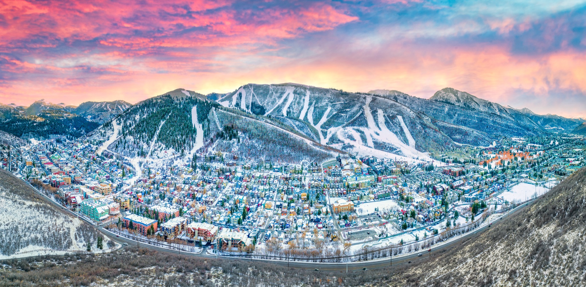 Snow-covered Park City and mountain ski slopes beneath a colorful sunset